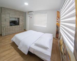 a bedroom with a white bed and a television at Luxury Eco Apartament in Playa Aguadulce