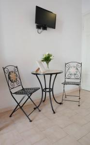 two chairs and a table with a tv on a wall at A casa di Mario e Nenè in Viareggio