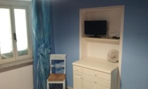a bedroom with a tv and a white dresser and a window at La casina di Silverio in Rio Marina