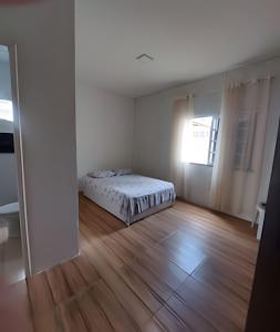 Casa Ilha de Itaparica Aratuba في Aratuba Beach: غرفة بيضاء مع سرير وأرضية خشبية