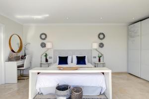 ein weißes Schlafzimmer mit einem weißen Bett und blauen Kissen in der Unterkunft Private Villa, Heated Pool Puerto Banus Marbella in Marbella