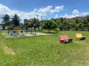 Casa ilha de Itaparica Aratuba 3 في Aratuba Beach: حديقة مع ملعب مع كراسي ملونة +9 صور