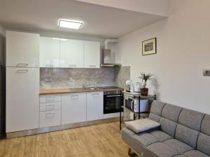 a kitchen with white cabinets and a couch in a room at Bijeg u mir, Dvosobni apartman in Pula