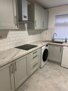 a kitchen with white cabinets and a sink and a dishwasher at The Peacock House 7 mins from Luton airport in Luton +27 photos
