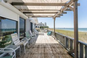 a porch with rocking chairs and the beach at Beachfront cottage on North Shore Grand Haven in Spring Lake