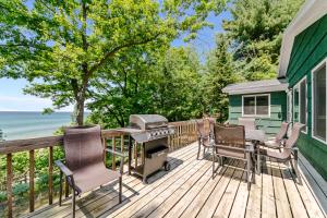 a deck with a grill and chairs on a house at Whiskey Creek Cottage- Private Lake Michigan Beach Frontage in Rothbury
