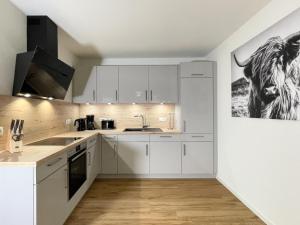 een keuken met witte kasten en een afbeelding van een koe aan de muur bij Herz von Kellenhusen 6 - Moje Koje in Kellenhusen