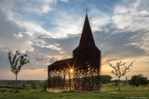 a large wooden structure in a field with the sunset at Vakantiehuis 2 Wheels 2 Relax in Wellen