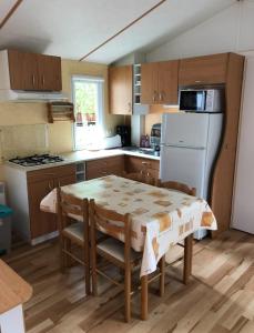 Una cocina con una mesa y un refrigerador blanco. en Oree du bois, en Besse-et-Saint-Anastaise