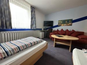 a hotel room with a bed and a table and a couch at Zeitwohnen Wolfsburg, ehemals Hotel am Klieversberg ein Unternehmen der Micha'S Hotelbetriebe in Wolfsburg +67 photos