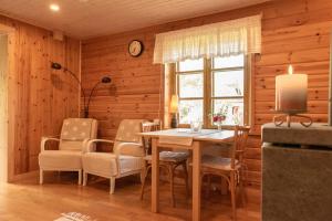 a dining room with a table and chairs and a clock at Ireneborg, cottage with Finnish sauna in Svedja