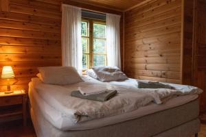 a bed in a wooden room with a window at Ireneborg, cottage with Finnish sauna in Svedja