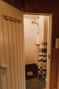 a bathroom with a shower with a black and white shower curtain at Ireneborg, cottage with Finnish sauna in Svedja