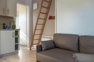 a living room with a couch and a ladder at Typ C2 Mini Lodge - Kalama Beach Park 1 in Pelzerhaken