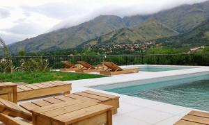 una piscina con sillas y vistas a las montañas en Parque Los Nogales Apart Hotel en Merlo