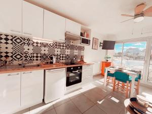 a kitchen with white cabinets and a table with chairs at Magnifique T2 au calme avec une superbe vue sur le port in Canet-en-Roussillon