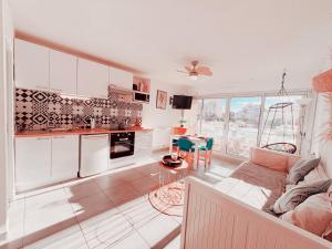 a kitchen with white cabinets and a living room at Magnifique T2 au calme avec une superbe vue sur le port in Canet-en-Roussillon