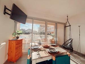 a dining room with a table and a large window at Magnifique T2 au calme avec une superbe vue sur le port in Canet-en-Roussillon