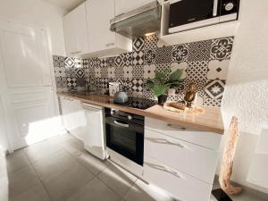 a kitchen with white cabinets and black and white tiles at Magnifique T2 au calme avec une superbe vue sur le port in Canet-en-Roussillon