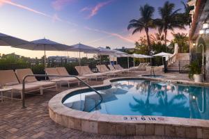 a swimming pool with lounge chairs and umbrellas at The Hotel Zamora in St. Pete Beach