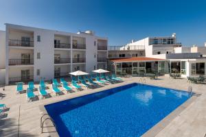 Un hotel con piscina y sillas y un edificio. en Aparthotel Vibra Club Maritim, en Bahía de San Antonio