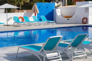 Un grupo de sillas junto a una piscina. en Aparthotel Vibra Club Maritim, en Bahía de San Antonio 43 fotos más