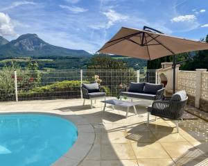 a patio with an umbrella and chairs and a pool at Mon espace bien-être in Ponsonnas