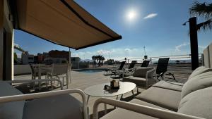 a patio with couches and tables and chairs on a roof at Apartamento Calanegra con Piscina en Puerto de Mazarrón Costa Cálida in Puerto de Mazarrón