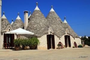 un edificio de piedra con techo y sombrilla en Masseria Peppeturro, en Cisternino