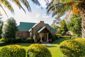 a house with a green roof and a yard with bushes at Andes Clarens Guesthouse in Clarens
