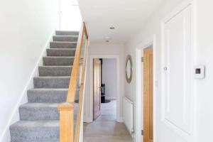 a staircase in a home with white walls and wooden floors at Beach house for 10 with hot tub & garden in West Wittering