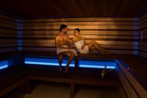 un hombre y una mujer sentados en una sauna en Hotel Astoria, en Canazei