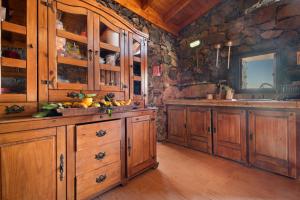 a kitchen with wooden cabinets and a stone wall at Finca Rural House Tenerife Relax in Santa Úrsula +21 photos
