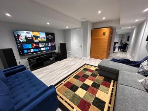 un soggiorno con divano e TV a schermo piatto di Ravine Retreat - 3RM Suite, 2BD, 1 WR, Pool, Sauna a Whitby