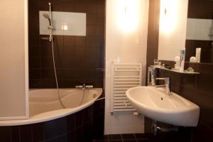 a bathroom with a sink and a bath tub at Résidence Le Beauséjour by Popinns in Plombières-les-Bains