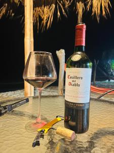 una bottiglia di vino e un bicchiere su un tavolo di Bungalows Sol y Mar a Canoas De Punta Sal