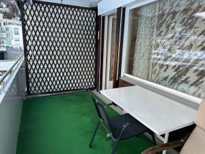 a table and chair on a balcony with green flooring at Haus Bündabrücke in Davos