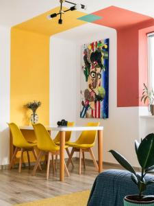 a dining room with a table and yellow chairs at Ultracentral cozy art apartment in Bacău