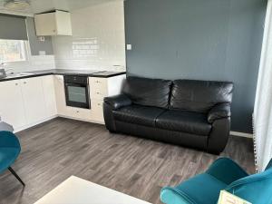 a living room with a black leather couch in a kitchen at Chalet 75 in Mundesley