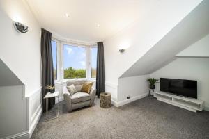 a living room with a tv and a chair at 2-Bed Apartment Sleeps 5 - Near Royal Alexandria Hospital - Free Parking & Longs Stays Available in Paisley