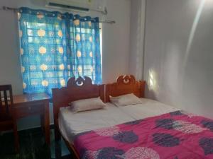 a bedroom with a bed and a desk and a window at Stay Castle in Guruvāyūr