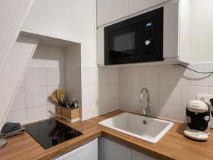 a kitchen with a sink and a microwave at Le Petit Nid - cozy comfort close to Paris in Clichy