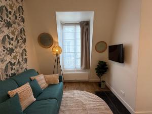 a living room with a blue couch and a window at Le Petit Nid - cozy comfort close to Paris in Clichy