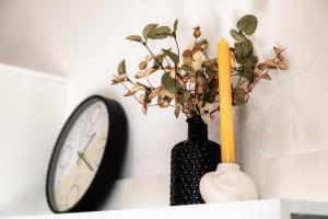 a black vase with a plant in it next to a clock at UBYTKO - Apartment in Blahová - Experience Rye Island in Blahová