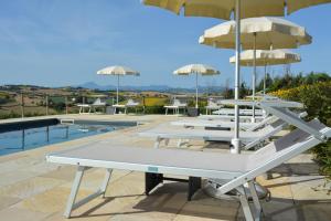 a row of lounge chairs with umbrellas next to a pool at casale dei cinque colli APPARTAMENTO in Ostra