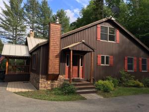 a brown house with red doors and a brick at Adirondack Luxury Getaway in Eagle Bay
