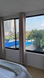 a bedroom with a large window with a view of a pool at Acogedor Apartamento cerca al Mar in Cartagena de Indias