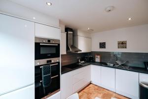 a kitchen with white cabinets and black appliances at Prosper House Apartment 3 in Norwich