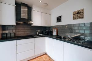 a kitchen with white cabinets and a sink at Prosper House Apartment 3 in Norwich