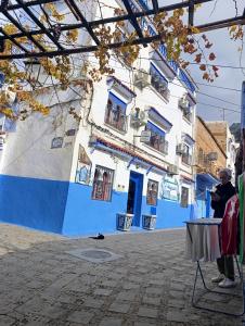 Hotel Chefchaouen في شفشاون: شخص يقف أمام مبنى أزرق وأبيض +37 صورة